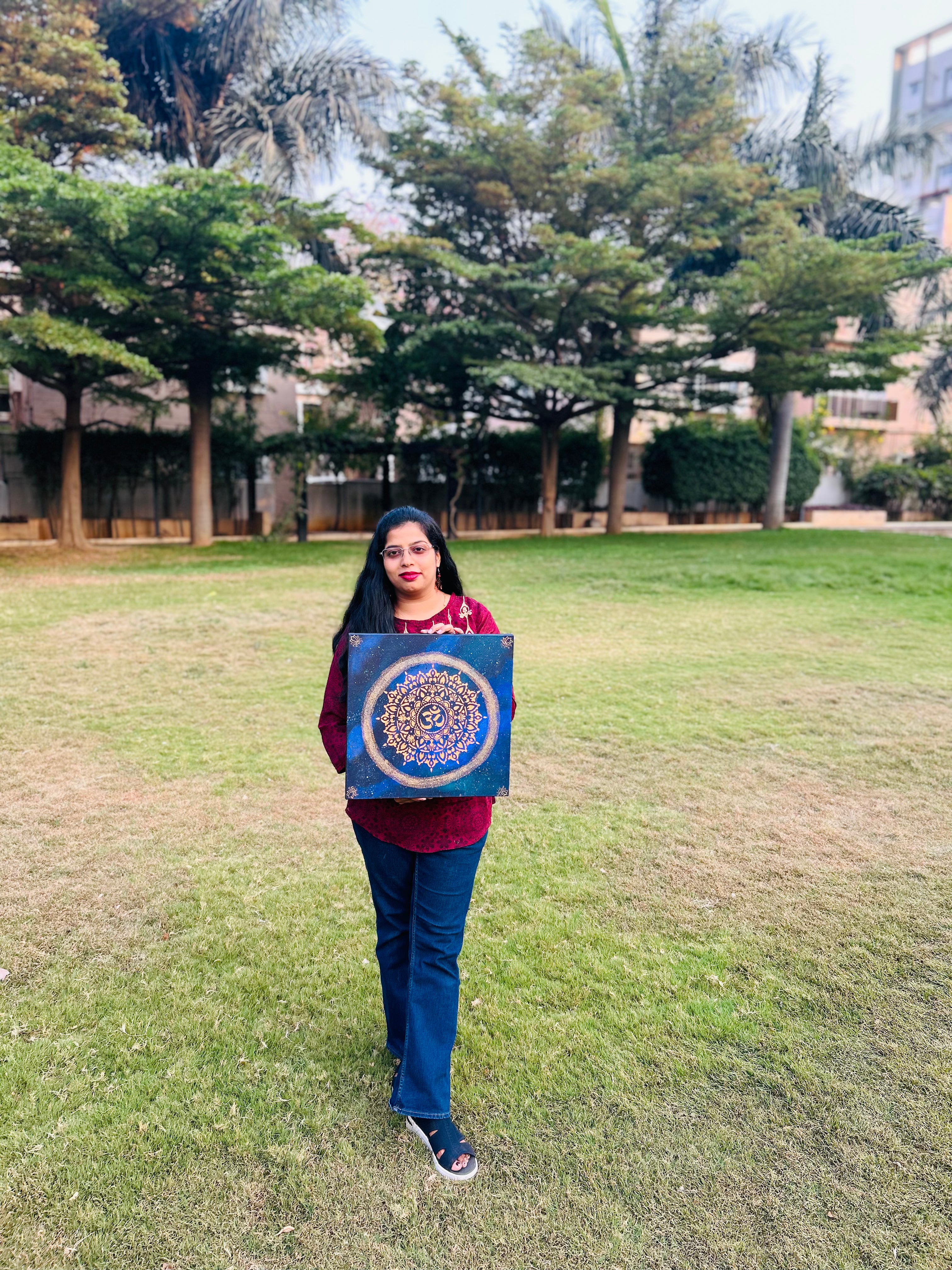 Person holding a blue mandala painting in a park
