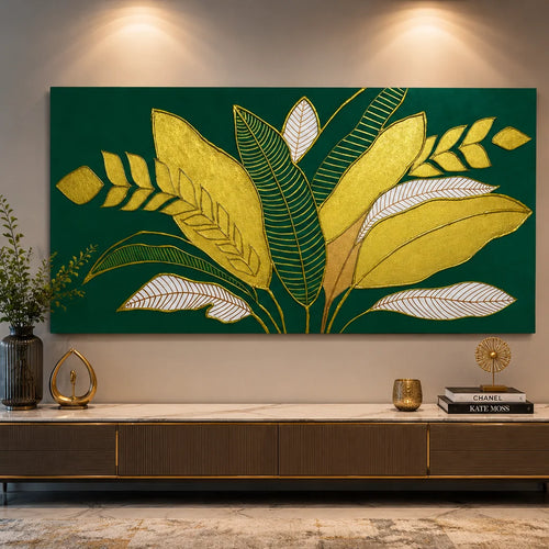 Large rectangular wall art featuring stylized tropical leaves in metallic gold and white on a deep green background, displayed above a console table in a modern interior setting.