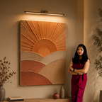 Woman standing in a room with a textured wall art piece and decorative items.