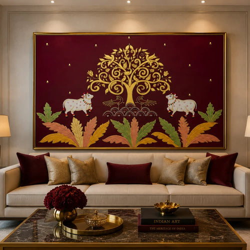 A large framed wall art piece hangs above a beige sofa in a styled living room. The artwork features a deep maroon background with a golden tree of life, two white cows, and multicolored leaves.